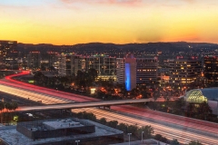 Sunrise over a highway in Irvine, California as headlight trails move through the roadways.